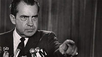 Richard Nixon unsuccessfully attempts to distract from the Watergate scandal by declaring "It's behind you!" during a Press Conference...
